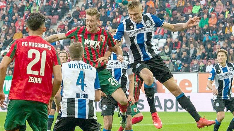 Augsburgs Andre Hahn (hinten, l) und Bielefelds Amos Pieper im Kopfballduell. Foto: Stefan Puchner/dpa