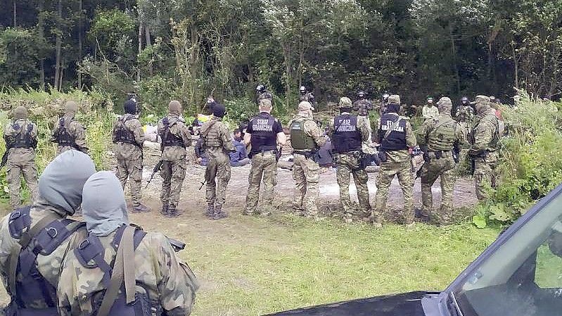 Migranten werden nach dem Grenzübertritt von Belarus nach Polen im Dorf Usnarz Gorny festgehalten. (Archivbild). Foto: Mateusz Wodziński/AP/dpa