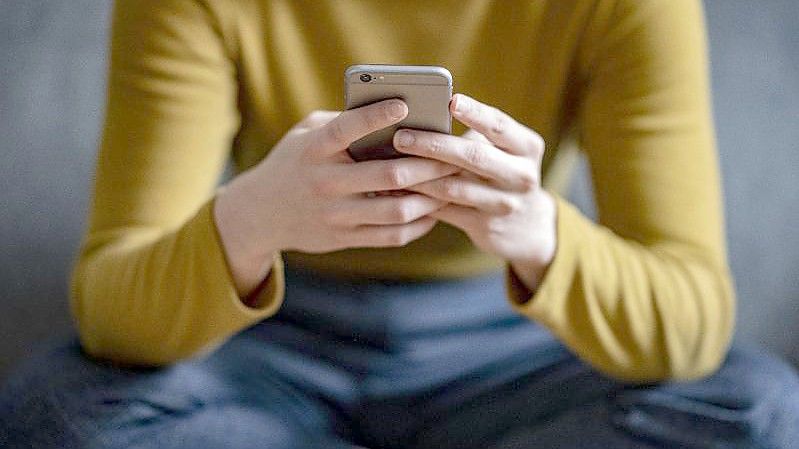 Eine junge Frau hält ein Smartphone in der Hand. Lustige Memes können Menschen dabei helfen, den mit der Corona-Pandemie verbundenen Stress besser zu bewältigen, indem sie deren Stimmung aufhellen. Foto: Fabian Sommer/dpa