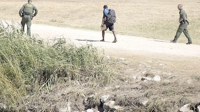 US-Grenzschutzbeamte sprechen mit einem haitianischen Migranten, der von Ciudad Acuna, Mexiko, in die USA eingereist ist. (Archivbild). Foto: Nick Wagner/XinHua/dpa