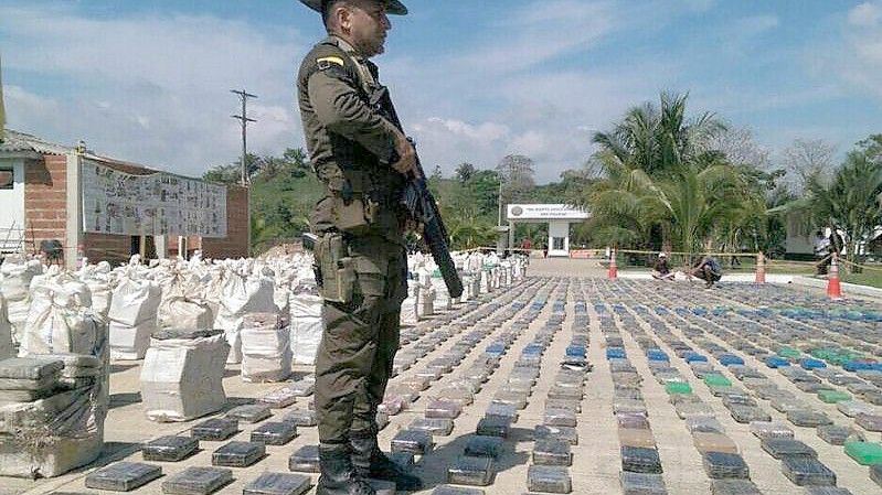 Ein von der kolumbianischen Polizei veröffentlichtes Handout-Bild zeigt einen kolumbianischen Polizeibeamten, der 2016 vor einer Auslage mit beschlagnahmten Kokainpaketen in Turbo, Kolumbien, Wache steht. (Archivbild). Foto: Colombian Police/EFE/COLOMBIAN POLICE/dpa
