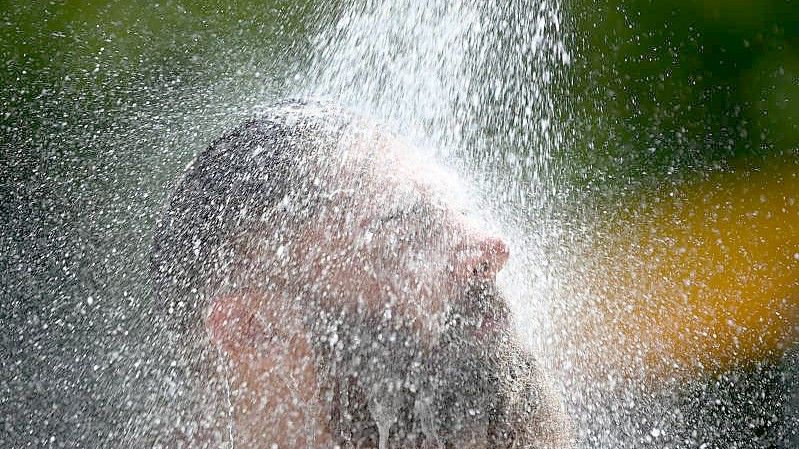 Ein Mann kühlt sich im Freibad unter einer Dusche ab. Foto: Patrick Seeger/dpa