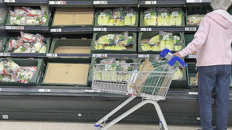 Eine Frau steht vor teilweise leeren Regalen in einem Supermarkt in London. Einem Bericht zufolge haben Versorgungsengpässe aufgrund der schärferen Einwanderungsregeln sowie von mehr Zöllen und Bürokratie die Lage in Großbritannien seit dem Brexit verschärft. Foto: Frank Augstein/AP/dpa
