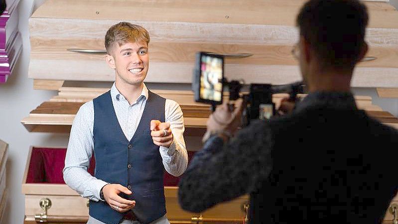Luis (l) und sein Vater Johannes Bauer vom Bestattungsunternehmen Burger filmen ein Video im Ausstellungsraum für ihre Social-Media Kanäle. Foto: Nicolas Armer/dpa