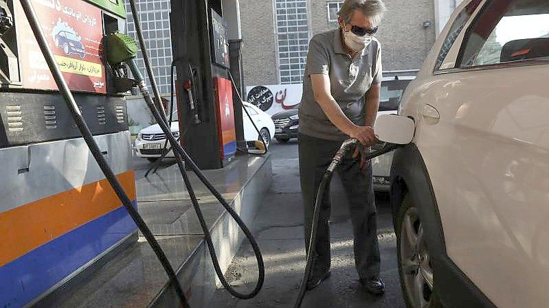 Ein Mann betankt sein Auto an einer Tankstelle. Der iranische Präsident hat den Cyberangriff auf das landesweite Zahlungssystem in Tankstellen scharf verurteilt. Foto: Vahid Salemi/AP/dpa