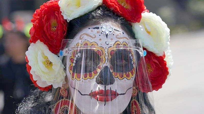 Eine als „Catrina“ verkleidete Frau trägt während der Feierlichkeiten zum Tag der Toten ein Gesichtsschild. Der Día de Muertos in Mexiko ehrt verstorbene Angehörige. Foto: Fernando Llano/AP/dpa