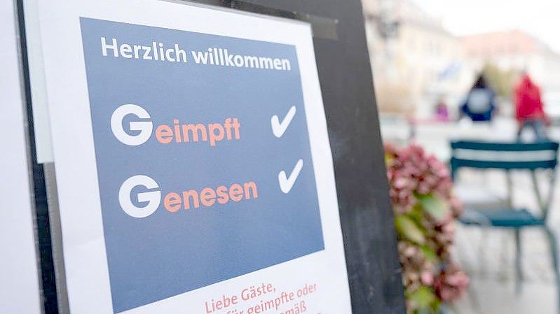 Eine Tafel vor einem Restaurant an der Hauptstraße informiert die Gäste über die 2G-Regel mit der Aufschrift „Geimpft Genesen“. Foto: Sebastian Kahnert/dpa-Zentralbild/dpa