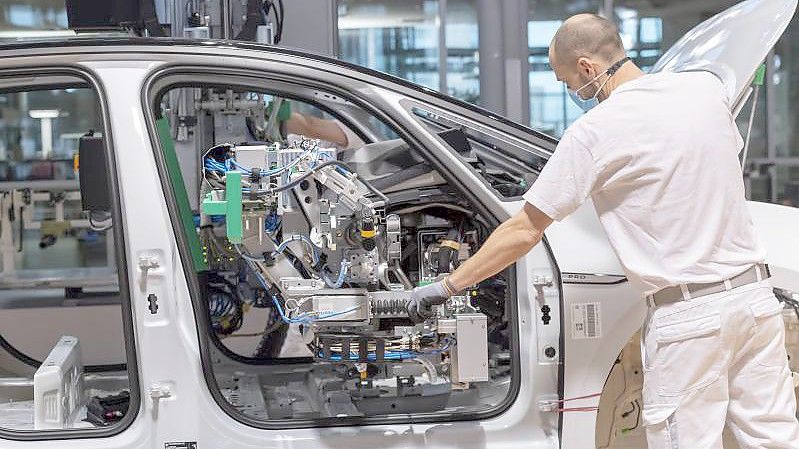 Ein Arbeiter arbeitet mit Mund-Nasen-Schutz an einem Auto. (Archivbild). Foto: Matthias Rietschel/dpa-Zentralbild/dpa