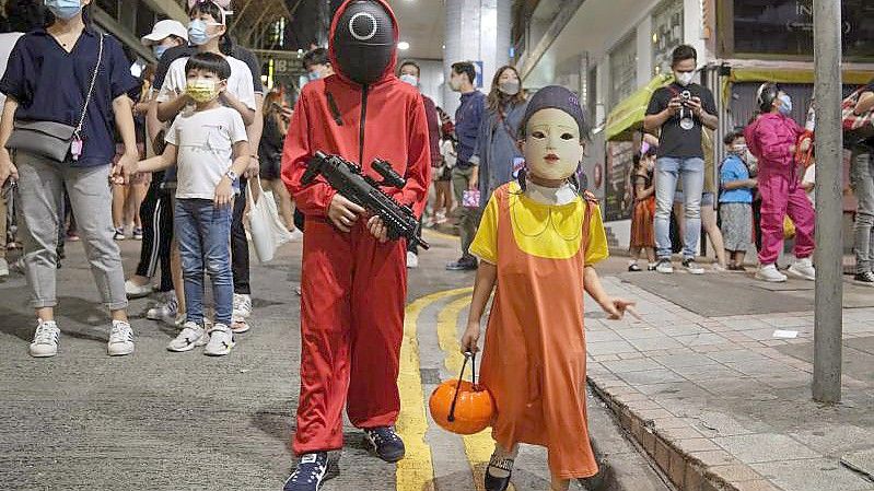 Kinder tragen anlässlich der Halloween-Feierlichkeiten Kostüme, die von der koreanischen Netflix-Originalserie „Squid Game“ inspiriert sind. Bei der Streamingserie „Squid Game“ sollten Eltern die Altersfreigabe ab 16 Jahren berücksichtigen, betonen Expertinnen. Foto: Kin Cheung/AP/dpa