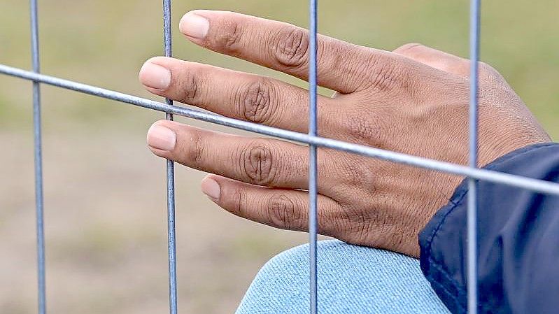 Die Hand eines Flüchtlings am Zaun einer Erstaufnahmeeinrichtung für Asylbewerber. Foto: Patrick Pleul/dpa-Zentralbild/ZB