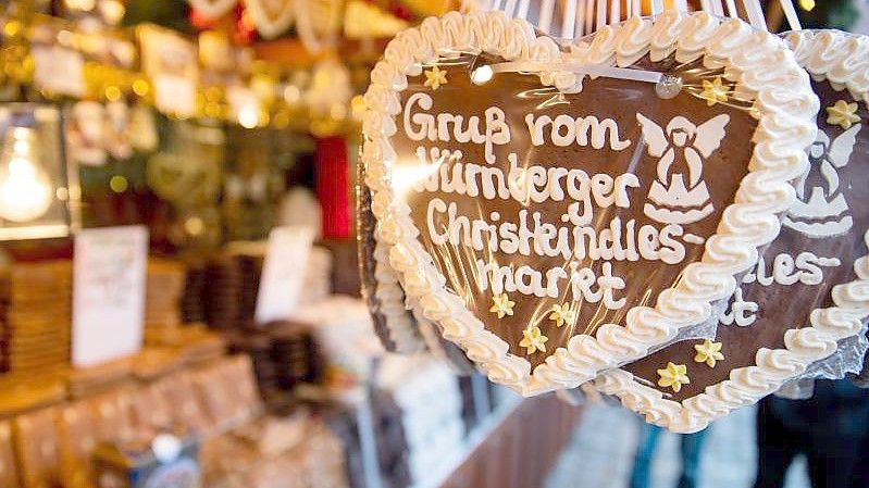 Lebkuchenherzen mit der Aufschrift „Gruß vom Nürnberger Christkindlesmarkt“ hängen an einem Stand auf dem Nürnberger Christkindlesmarkt. Foto: Daniel Karmann/dpa