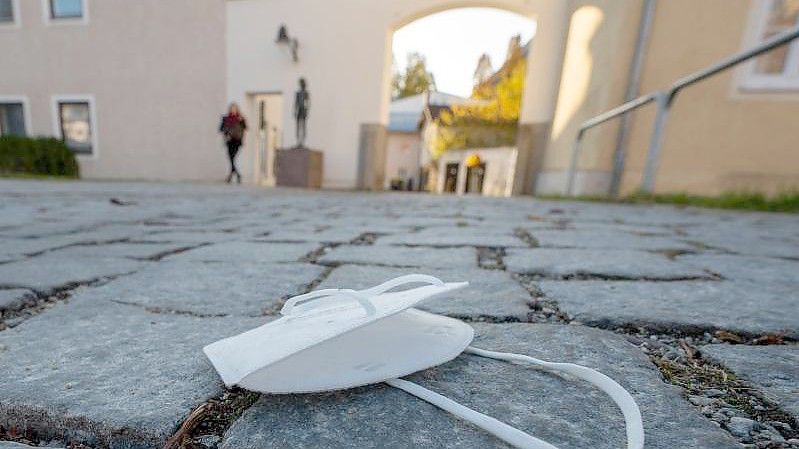 Eine FFP2-Maske liegt auf einem Weg in der Innenstadt von Pfarrkirchen in Bayern. Foto: Armin Weigel/dpa