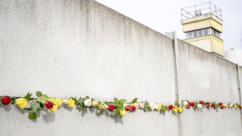 Rosen stecken bei der zentralen Gedenkveranstaltung zum 32. Jahrestag des Mauerfalls in der Gedenkstätte Berliner Mauer in einem Mauerstück. Foto: Fabian Sommer/dpa
