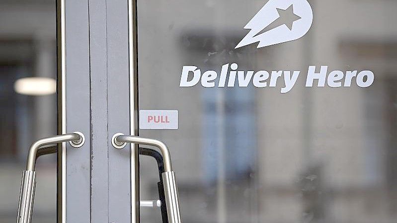 Das Logo Essenslieferdienstes Delivery Hero ist an einer Glasscheibe der Zentrale angebracht. Foto: Britta Pedersen/dpa-Zentralbild/dpa