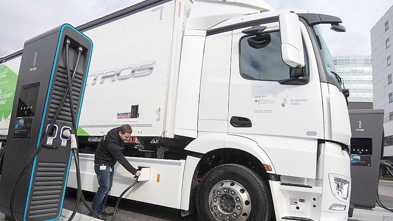 Ein Mitarbeiter der Daimler AG steckt einen Ladestecker in einen elektrisch angetriebenen Mercedes-Benz eActros. Foto: Marijan Murat/dpa