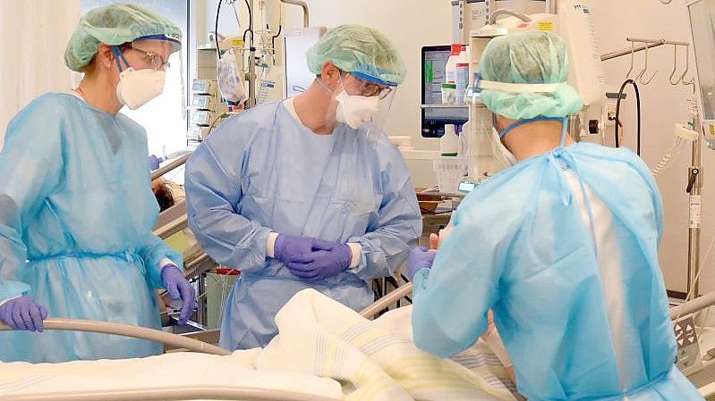 Auf der Covid-Station, einem Bereich der Operativen Intensivstation vom Universitätsklinikum Leipzig, stehen Mitarbeiter am Bett eines schwerkranken Patienten. Foto: Waltraud Grubitzsch/dpa-Zentralbild/dpa