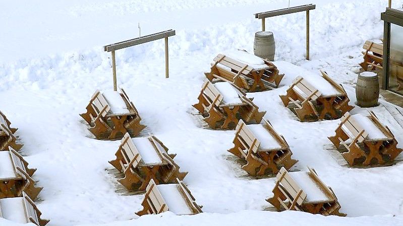 Schnee bedeckt Bänke und Tische an einer gesperrten Skipiste. Die österreichische Regierung hatte die Schließung der Skigebiete angeordnet, um die Ausbreitung des Coronavirus zu verlangsamen. Foto: Matthias Schrader/AP/dpa