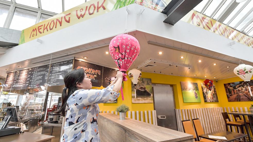 Die Mitarbeiterin eines asiatischen Imbisses sorgt in der Markthalle mit Dekoration für ein wenig Atmosphäre.