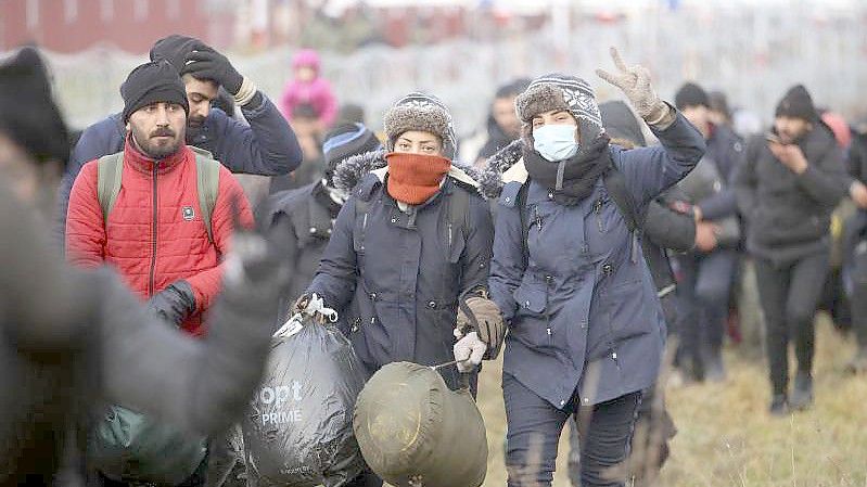 Migranten gehen entlang des Stacheldrahts, während sie sich an der belarussisch-polnischen Grenze versammeln. Foto: Leonid Shcheglov/BelTA-Pool/AP/dpa