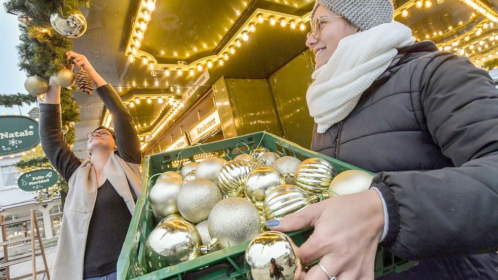 Die Schausteller sind so weit: Janice Weinobst (links) und Raluca Guragata haben in Aurich beim Aufbau des Weihnachtsmarktes geholfen. Wenn nichts dazwischen kommt, sollen die Stände bald öffnen. Foto: Ortgies
