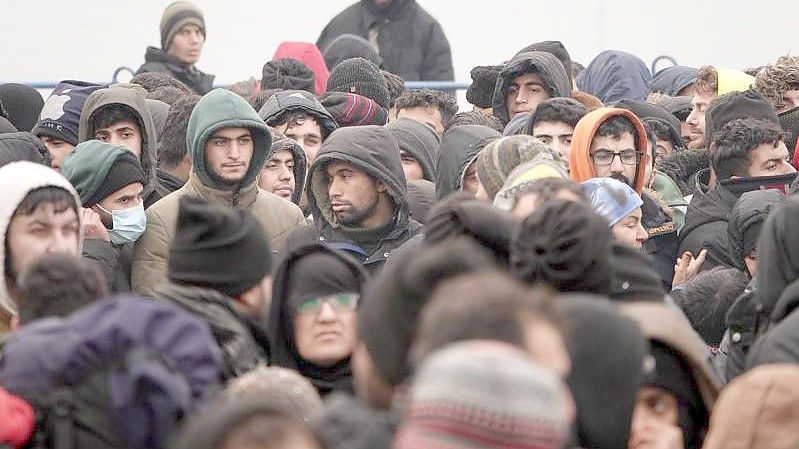 Migranten warten vor einer Lagerhalle in der Nähe der Grenze. Foto: Ulf Mauder/dpa