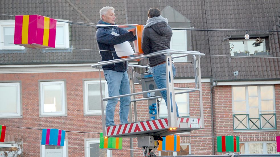 Bunte Geschenke schmücken den Neuen Markt in Emden. Mitarbeiter einer Emder Werbefirma hängten am Montag die Lichterketten auf. Fotos: H. Müller