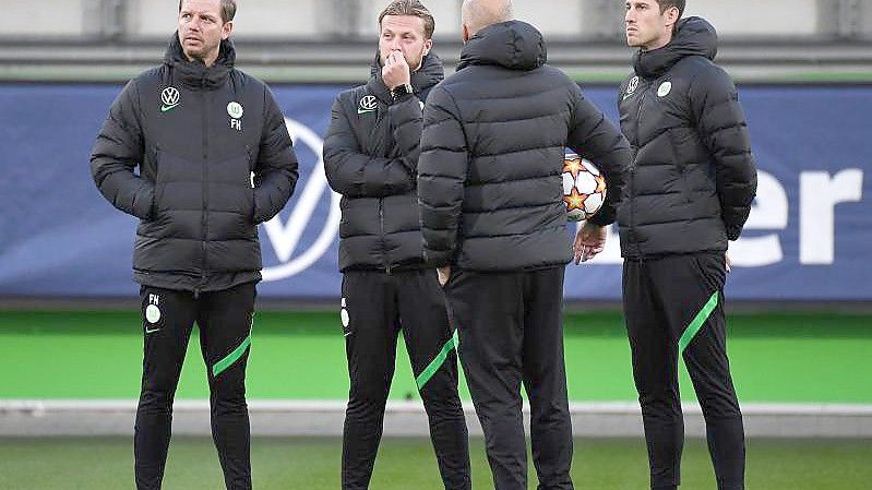 Vor dem Abflug nach Sevilla war Corona wieder ein Thema: Wolfsburgs Trainer Florian Kohfeldt (l) steht mit seinem Team zusammen. Foto: Swen Pförtner/dpa