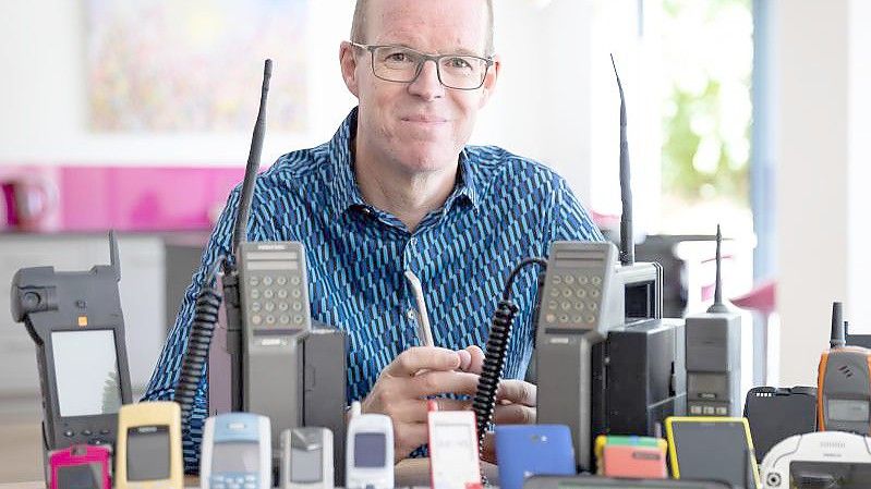 Ben Wood, Gründer des Museums, sitzt hinter einigen der über 2.000 einzigartigen Mobiltelefone, die jetzt Teil des Online-Museums sind. Foto: Mobile Phone Museum/Vodafone/PA Media/dpa/Archiv