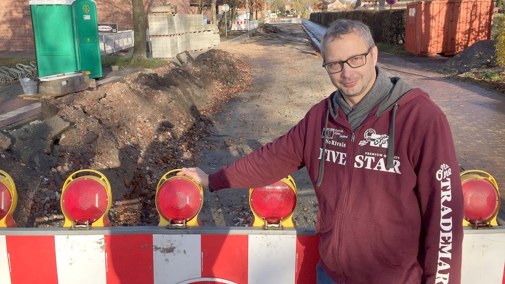 Hier steht Unternehmer Manfred Fecht vor der Baustellenabsperrung in der Straße Im Brink, die bis vor ein paar Tagen die Einfahrt zu seinem Pflanzencenter und die zur Zahnarztpraxis versperrte. Es habe gedauert, bis die Gemeinde bereit gewesen sei, die Absperrung zu versetzen, sagt Fecht. Foto: Schneider-Berents