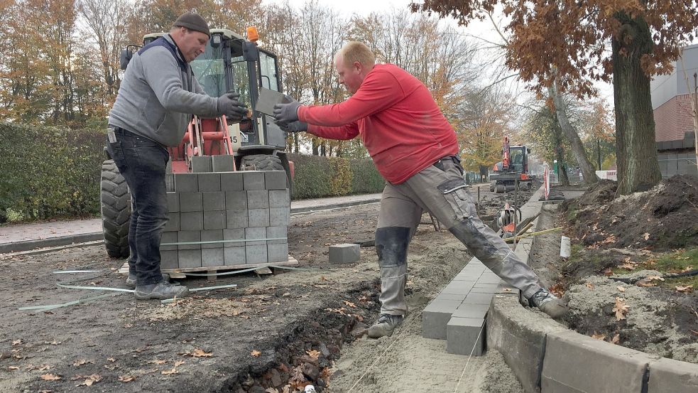 Eike Klaaßen (rechts) und Gerrit Harms, Mitarbeiter der Tell Bau GmbH aus Norden, verlegen hier neue Rinnensteine in der Straße Im Brink. Damit sind sie im ersten Bauabschnitt fertig. Foto: Schneider-Berents