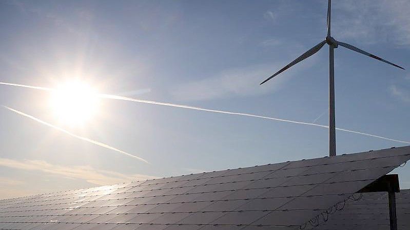 Ein Windrad steht hinter den Solarzellen einer Solarkraftanlage im Sonnenschein. Foto: Karl-Josef Hildenbrand/dpa