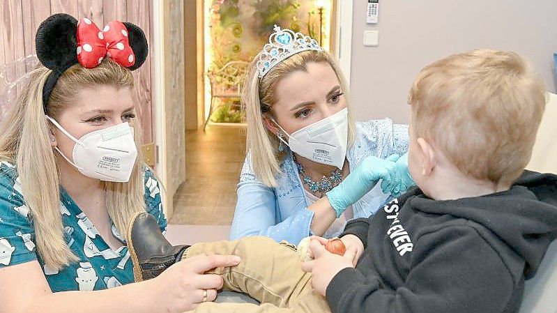 Kinderzahnärztin Anne Heinz (m.) verkleidet als Eiskönigin „Elsa“ und ihre Arzthelferin Ari Dema in der Kinderzahnarztpraxis „Dentiland“. Foto: Patrick Pleul/dpa-Zentralbild/ZB