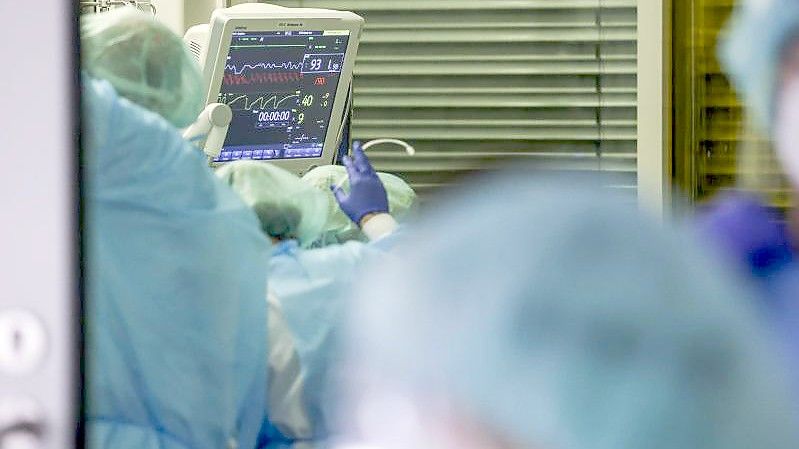 Ein Facharzt und mehrere Intensivpfleger versorgen einen Covid-19-Patienten auf der Intensivstation der Leipziger Uniklinik. Foto: Jan Woitas/dpa