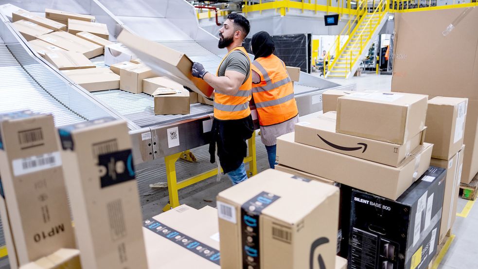 Mitarbeiter des Paketversenders Amazon sortieren Pakete. Foto: Peter Steffen/dpa