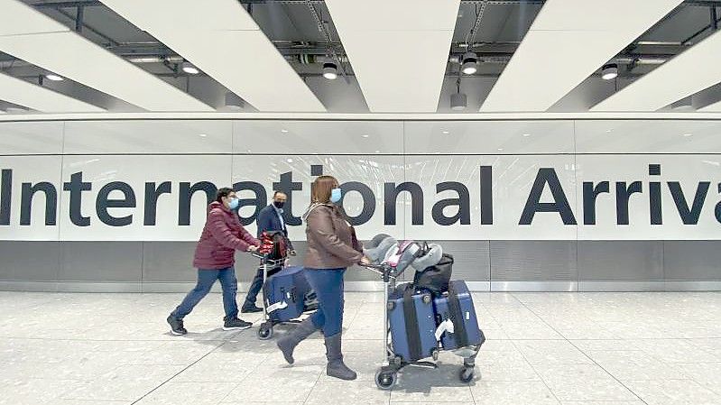 Passagiere gehen mit ihrem Gepäck durch das Ankunftsterminal eines Flughafens. Symbolbild. Foto: Alberto Pezzali/AP/dpa