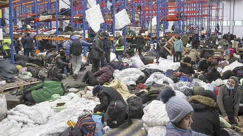 Migranten, die sich für die Nacht im Logistikzentrum am Kontrollpunkt „Kuznica“ an der belarussisch-polnischen Grenze einrichten. Foto: Maxim Guchek/BelTA/AP/dpa
