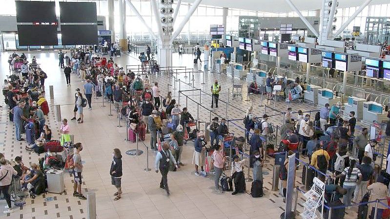 Reisende stehen am Flughafen in Kapstadt in langen Schlangen an den wenigen Schaltern an, die überhaupt noch offen sind. Foto: Kristin Palitza/dpa