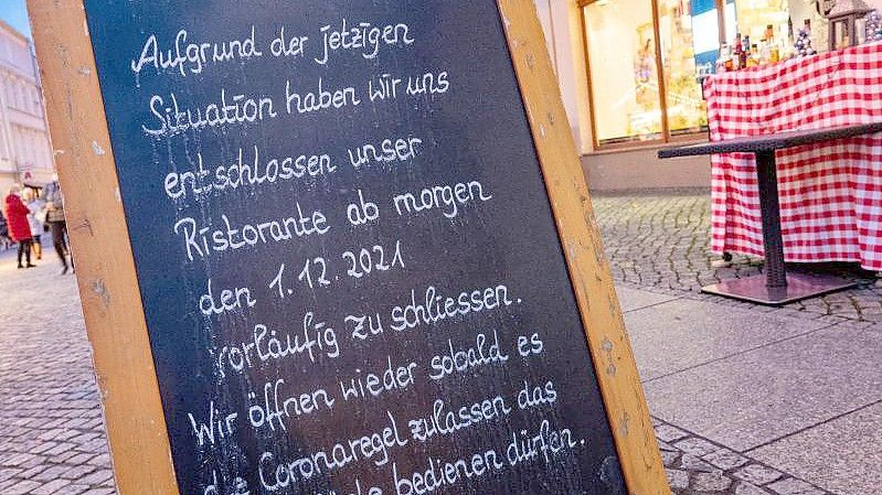 Ein Schild zur Schließung am Eingang zu einem Restaurant am Markt in Greifswald. Foto: Stefan Sauer/dpa