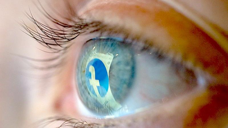 Das Facebook-Logo spiegelt sich in einem Auge. Foto: Mohssen Assanimoghaddam/dpa