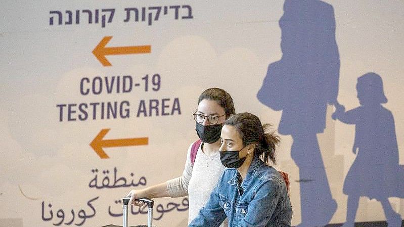 Reisende mit Mund-Nasen-Schutz kommen am Ben-Gurion-Flughafen an. Israel hat die Handy-Überwachung von Omikron-Infizierten beendet. Foto: Ariel Schalit/AP/dpa
