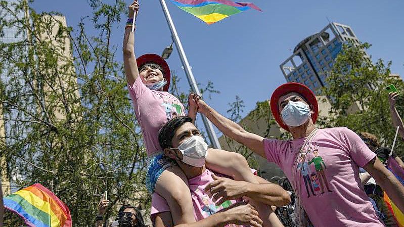 Eine Familie nimmt fahnenschwenkend an der jährlichen Gay Pride Parade in Chiles Hauptstadt teil. Foto: Esteban Felix/AP/dpa