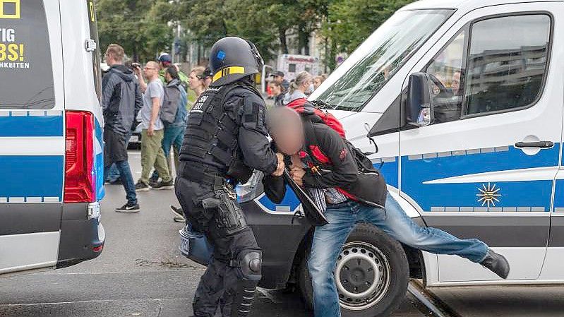 Ein Polizist hält einen Teilnehmer einer nicht genehmigten Demonstration gegen die Corona-Politik fest. (Archivbild). Foto: Christophe Gateau/dpa