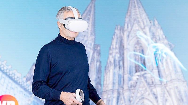Vodafone-Chef Ametsreiter blickt mit einer Virtual-Reality-Brille auf den digitalen Zwilling des Kölner Doms. Foto: Rolf Vennenbernd/dpa