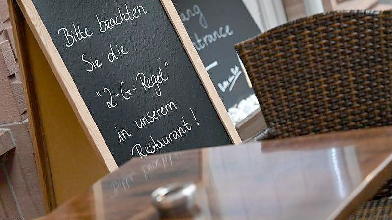 Auf einer Tafel vor einem Restaurant am Frankfurter Römerberg steht der Hinweis „Bitte beachten Sie die “2-G-Regel„ in unserem Restaurant!“. Foto: Arne Dedert/dpa