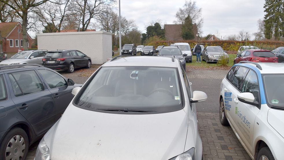 Gegen Mittag bei der Grundschule Flachsmeer: Der vorhandene Parkplatz (vorne) ist vollgeparkt, viele Eltern stellen deshalb ihre Fahrzeuge auf der neuen Grünfläche (hinten) ab, wo zuvor ein Wohnhaus stand. Foto: Ammermann