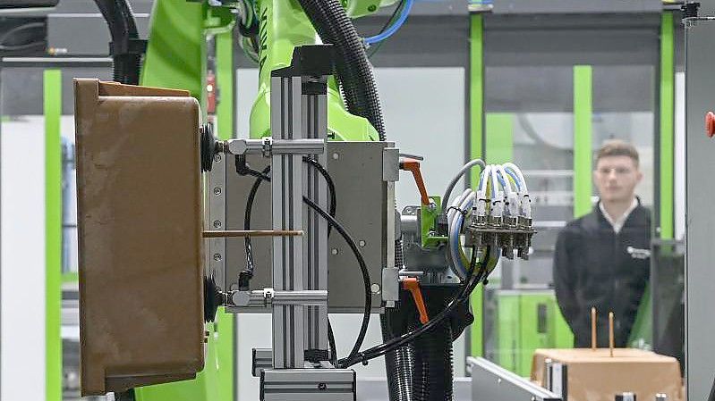 Ein Probebauteil wird im neuen Technikum des Fraunhofer-Pilotanlagenzentrums für Polymersynthese und -verarbeitung PAZ von einem Roboter aus einer Spritzgussanlage entnommen. Foto: Hendrik Schmidt/dpa-Zentralbild/dpa