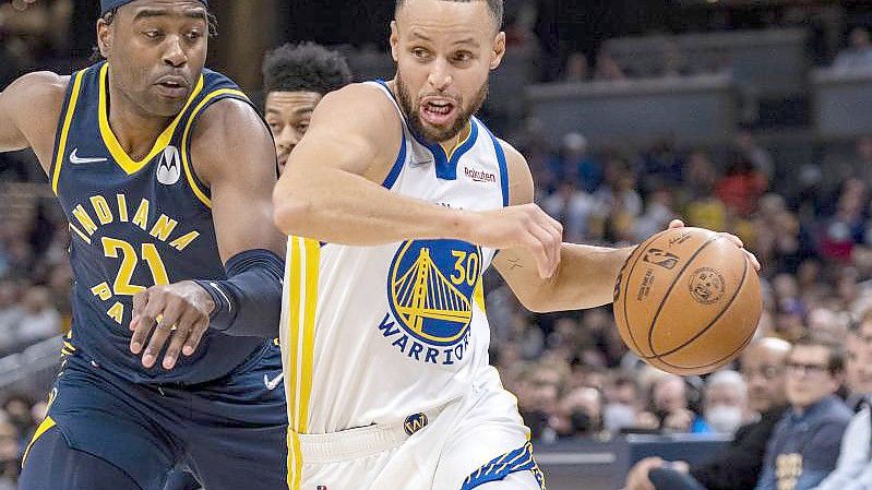 Stephen Curry (30), Guard der Golden State Warriors, spielt den Ball in der ersten Halbzeit an Kelan Martin (21), dem Guard der Indiana Pacers, vorbei. Foto: Doug Mcschooler/AP/dpa