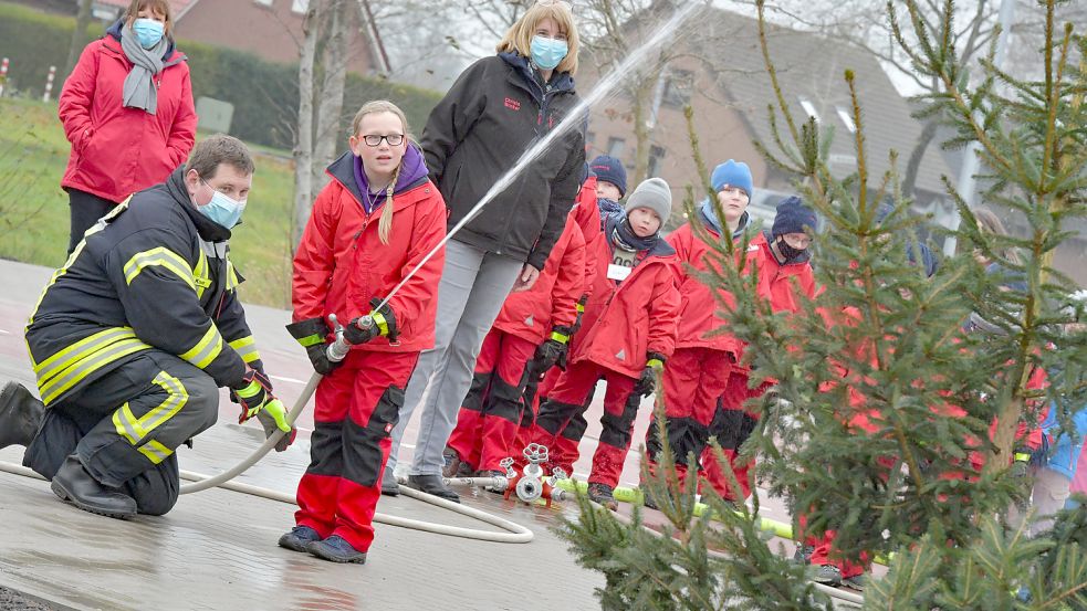 Die Kinder unterstützen die Feuerwehrmänner beim Löschen.