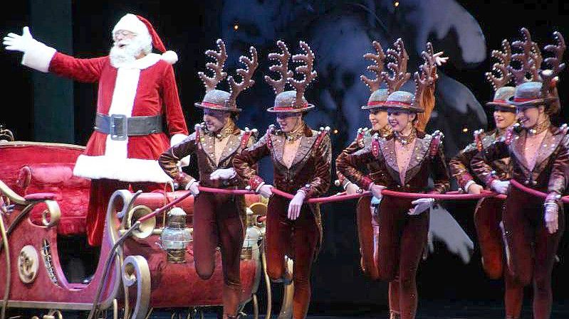 Mitglieder der Tanztruppe „Rockettes“ ziehen während einer Aufführung im Jahr 2018 einen Schlitten mit einem Weihnachtsmann über die Bühne. Foto: Christina Horsten/dpa