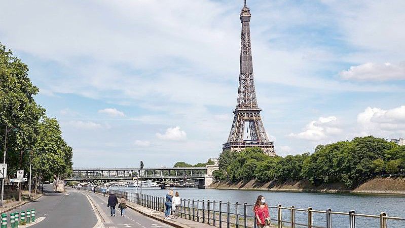 Menschen spazieren an der Seine neben dem Eiffelturm. Die Bundesregierung stuft Frankreich seit Mitternacht als Hochrisikogebiet ein. Foto: Thomas Samson/AFP/dpa